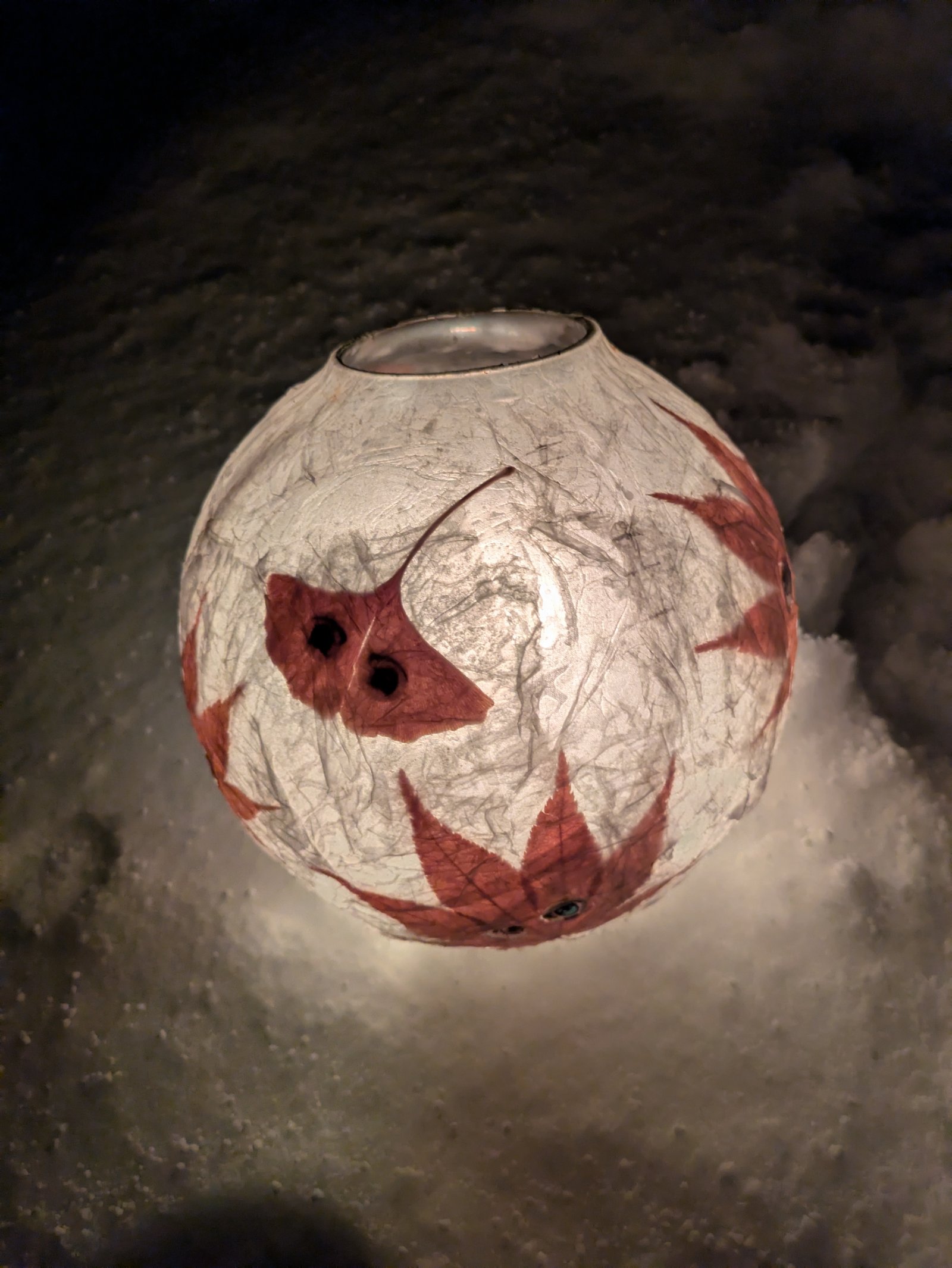 雪の上で灯る、紅葉とイチョウの葉を貼った和紙の丸いランタン