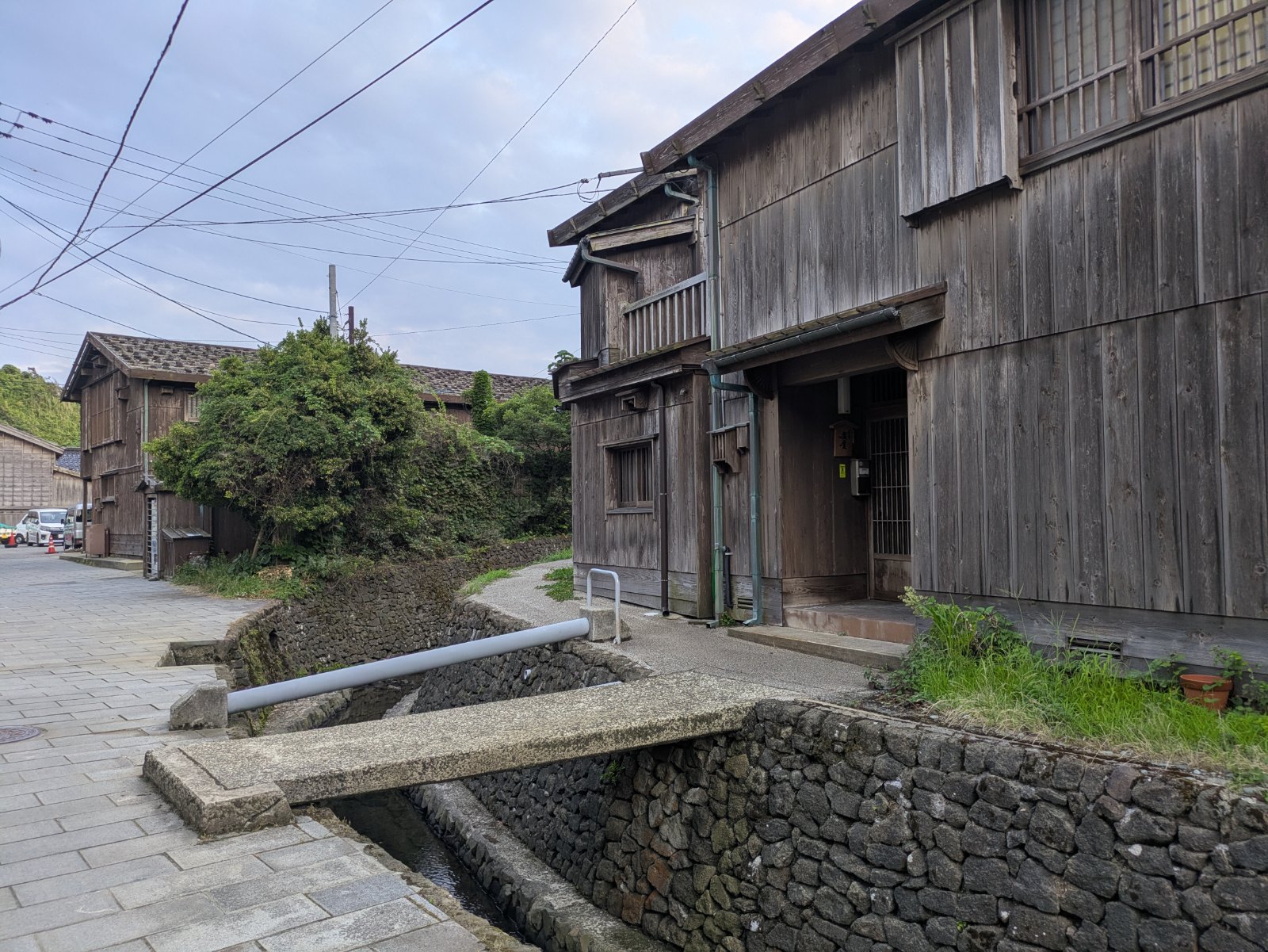縦板張りの木造家屋と石積みの水路が続く佐渡島・宿根木集落の路地