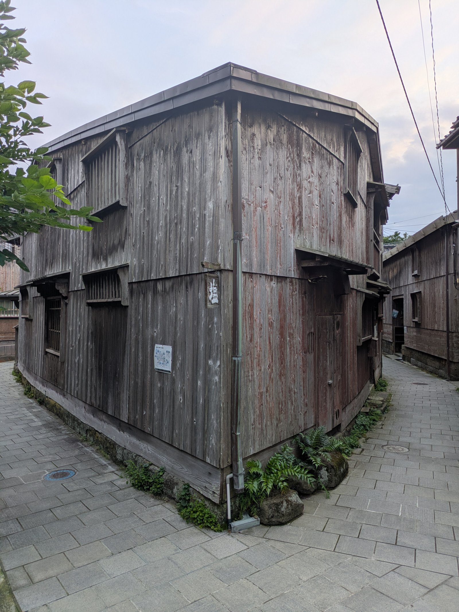 宿根木集落の石畳の路地の分かれ道に建つ、板張りの古い木造二階建ての家