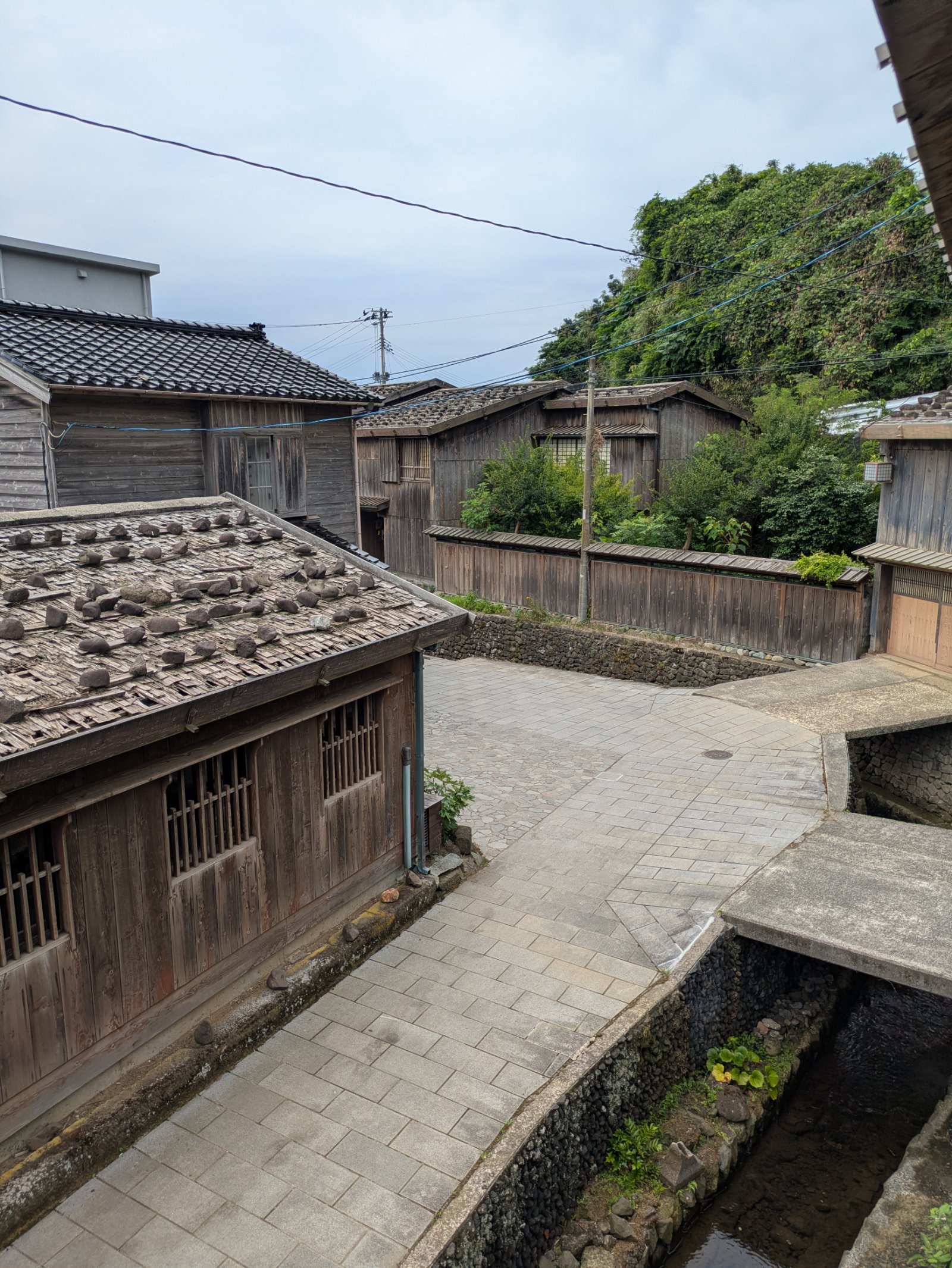 石置き屋根の木造家屋と石畳の小道、水路が続く宿根木集落の町並み