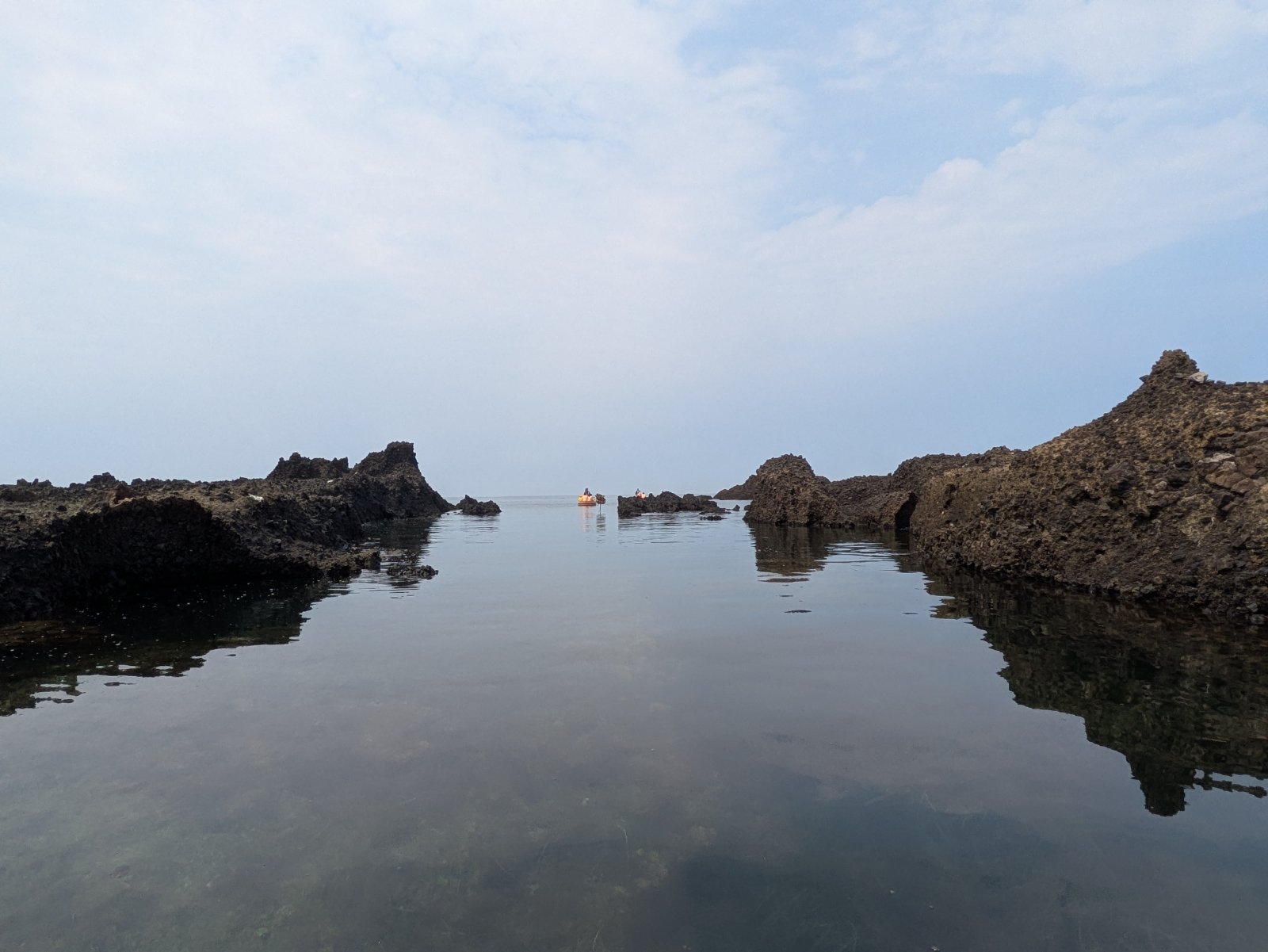 岩場に囲まれた静かな入江と、沖合に浮かぶたらい船（宿根木）