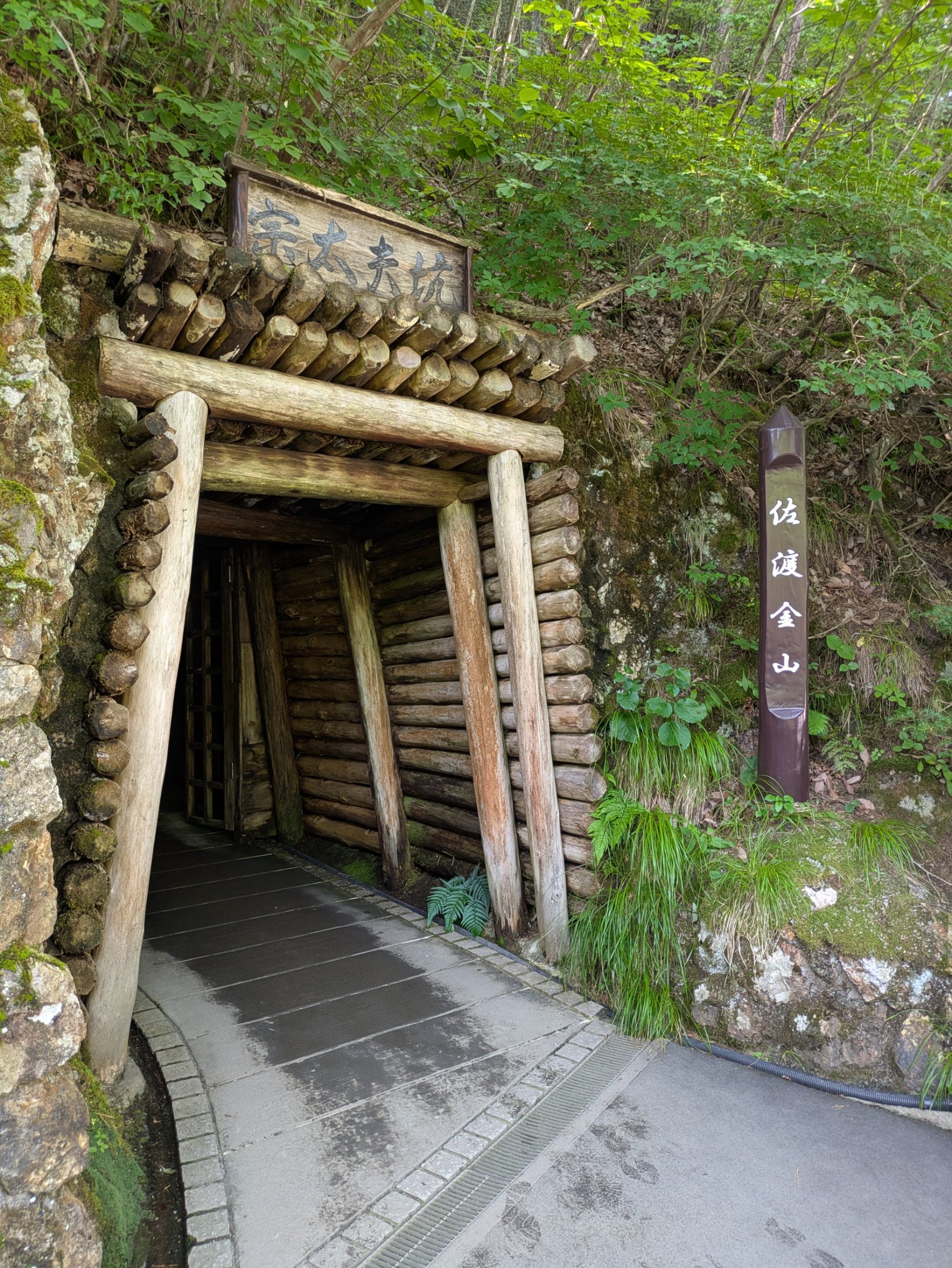 木組みの坑口に「宗太夫坑」の看板が掛かる佐渡金山の入口、脇に「佐渡金山」の標柱