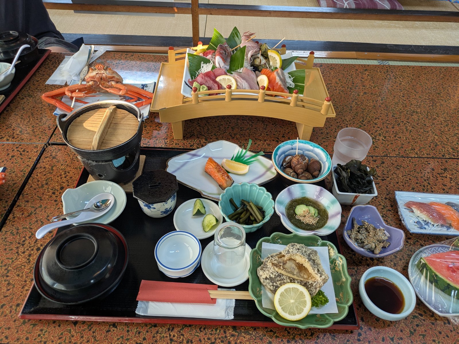 長浜荘の夕食。橋形の器に盛った刺身、茹でた蟹、焼き鮭、天ぷら、小鉢、握り寿司が並ぶ座敷の膳