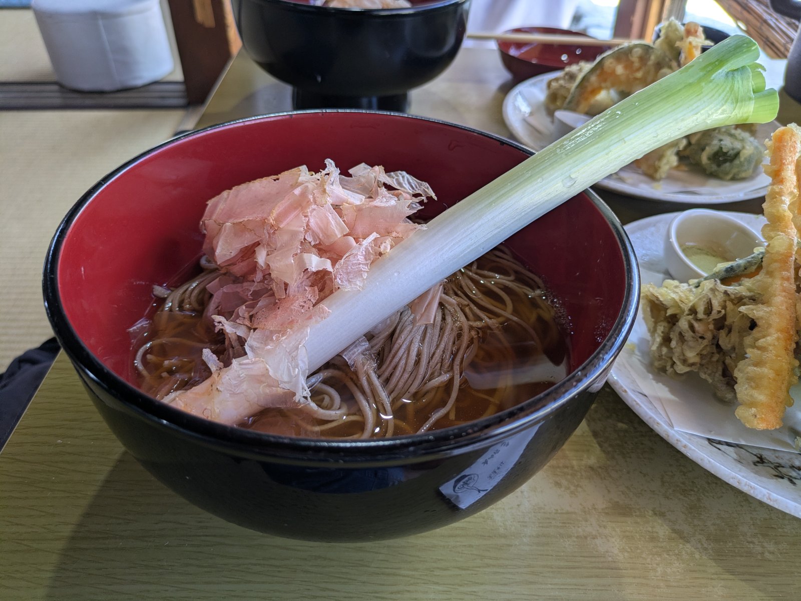 長ネギが一本丸ごと添えられ、かつお節がのった大内宿名物のねぎそばと野菜の天ぷら