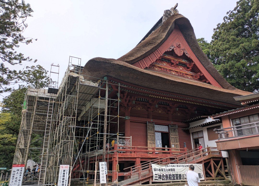足場が組まれ茅葺き屋根の葺き替え工事中の出羽三山神社・三神合祭殿