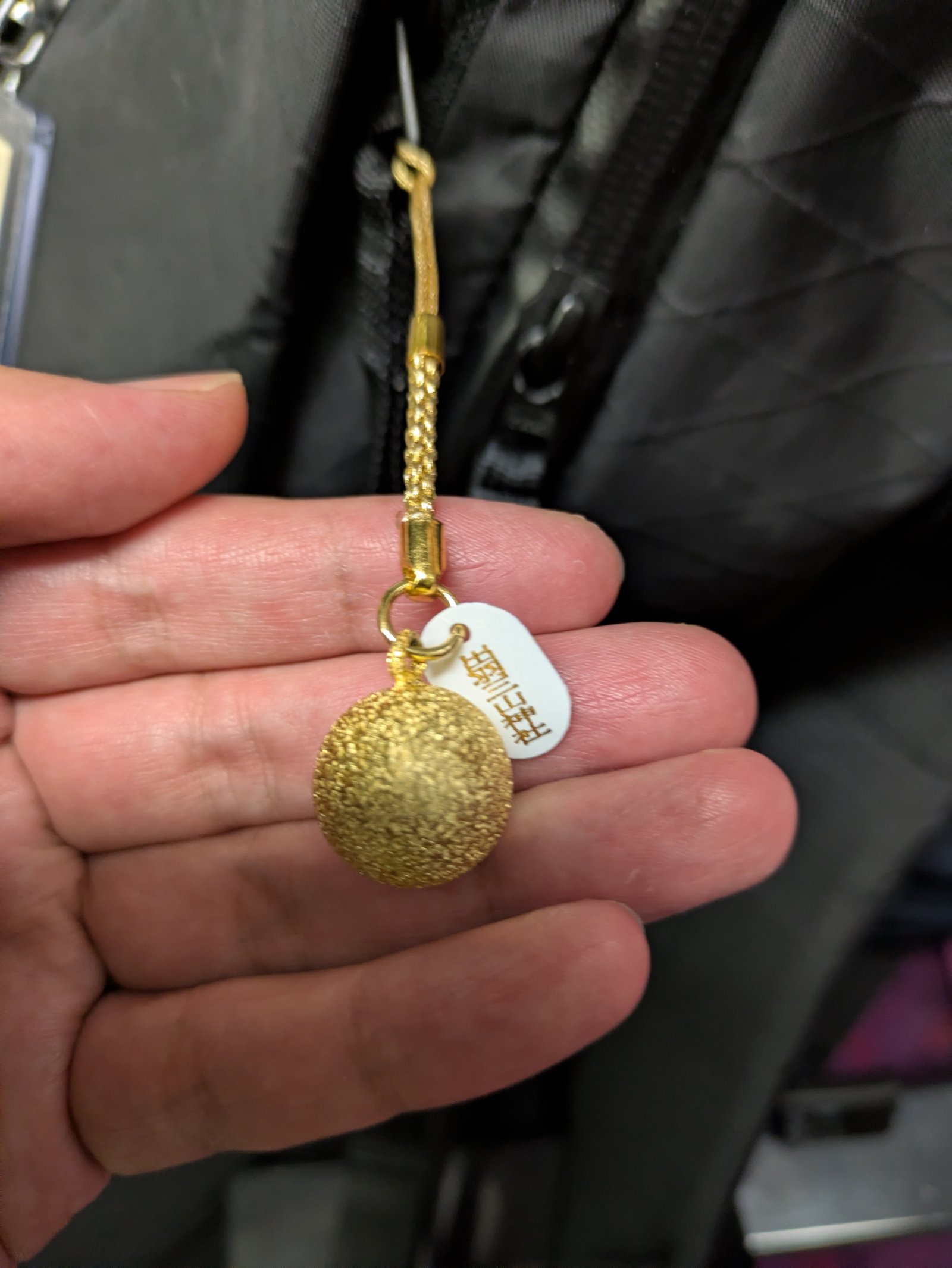 手のひらに載せた出羽三山の金色の鈴のお守り