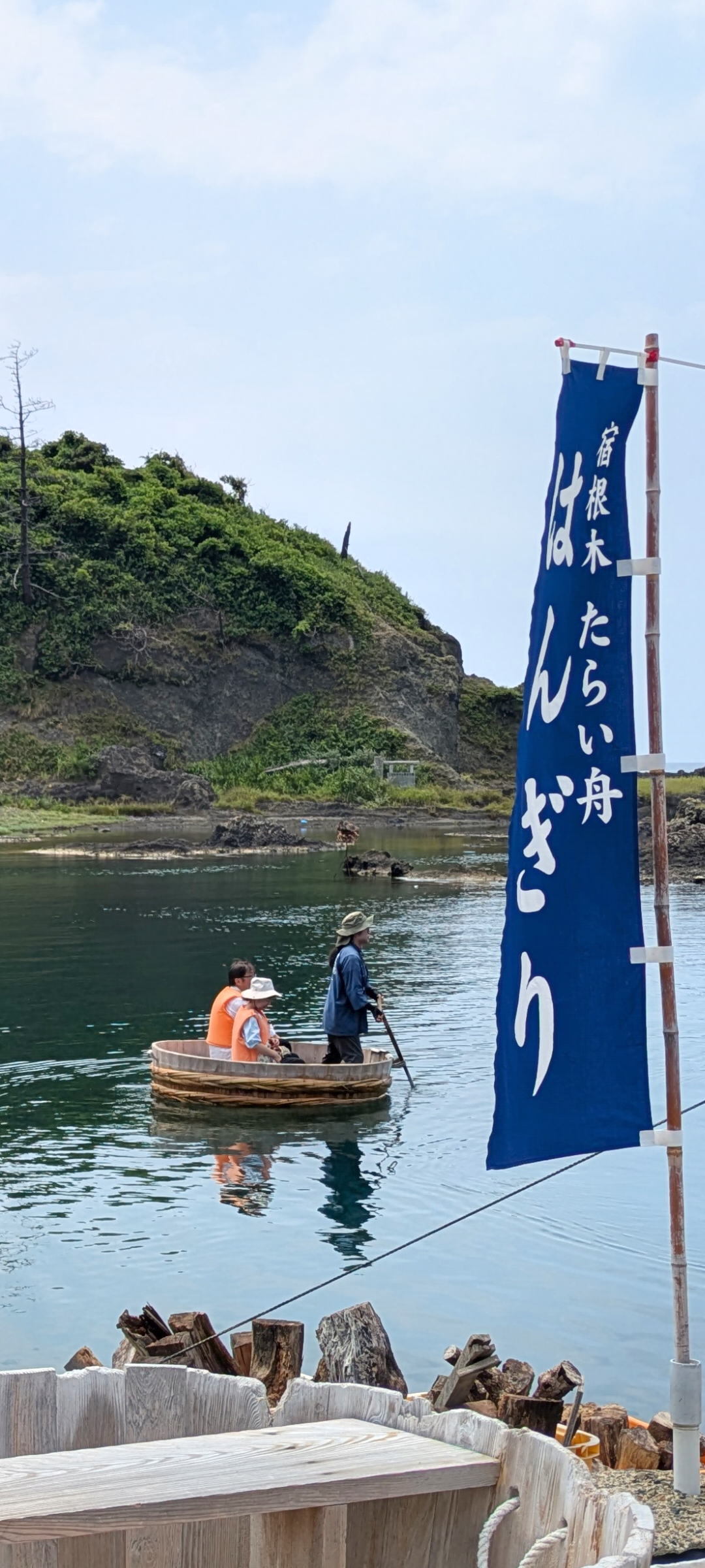 宿根木の入り江を進むたらい舟と「宿根木 たらい舟 はんぎり」と書かれた青いのぼり
