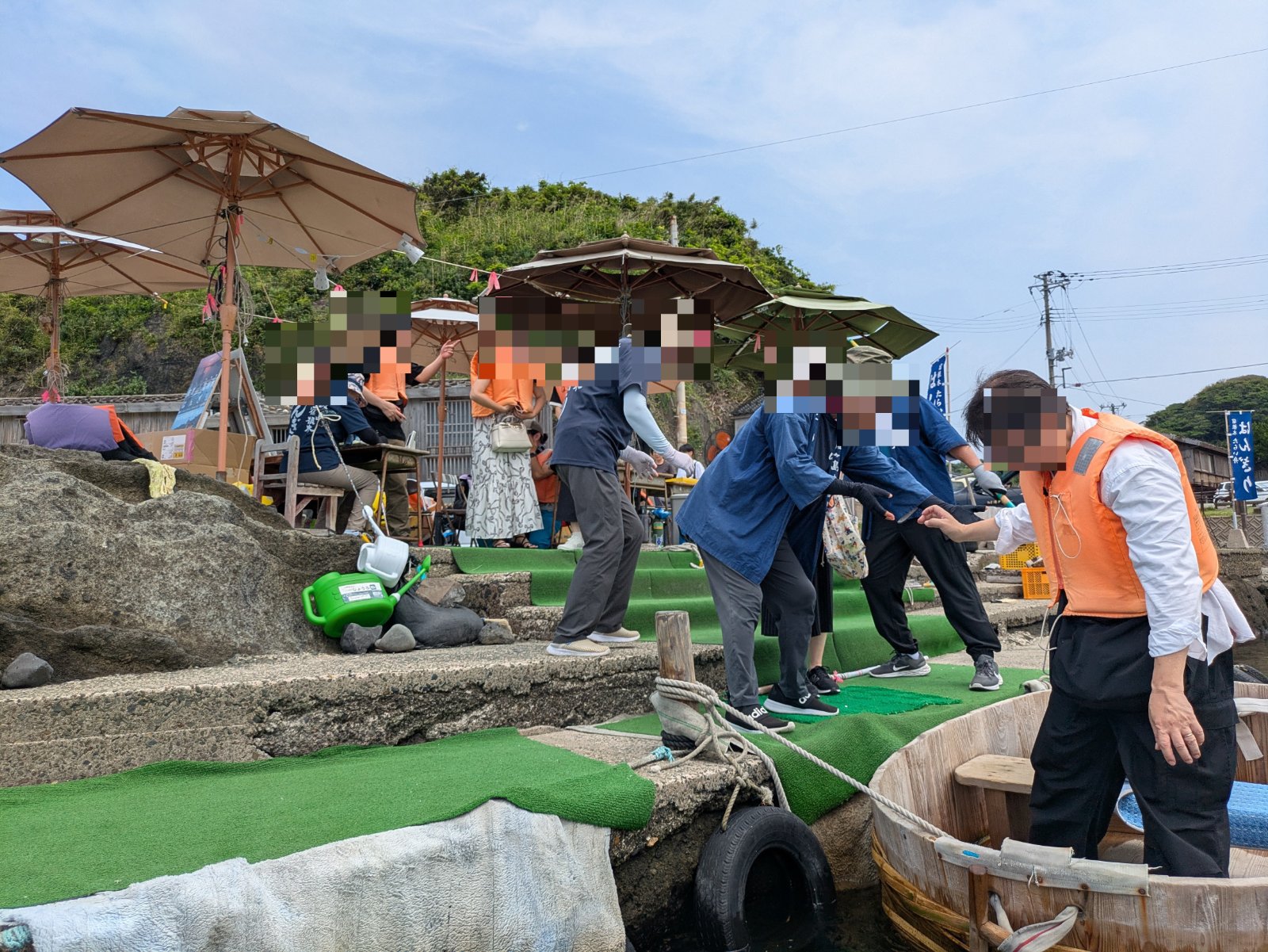 宿根木の岸壁から係員に手を取られてたらい船に乗り込む救命胴衣姿の乗船客