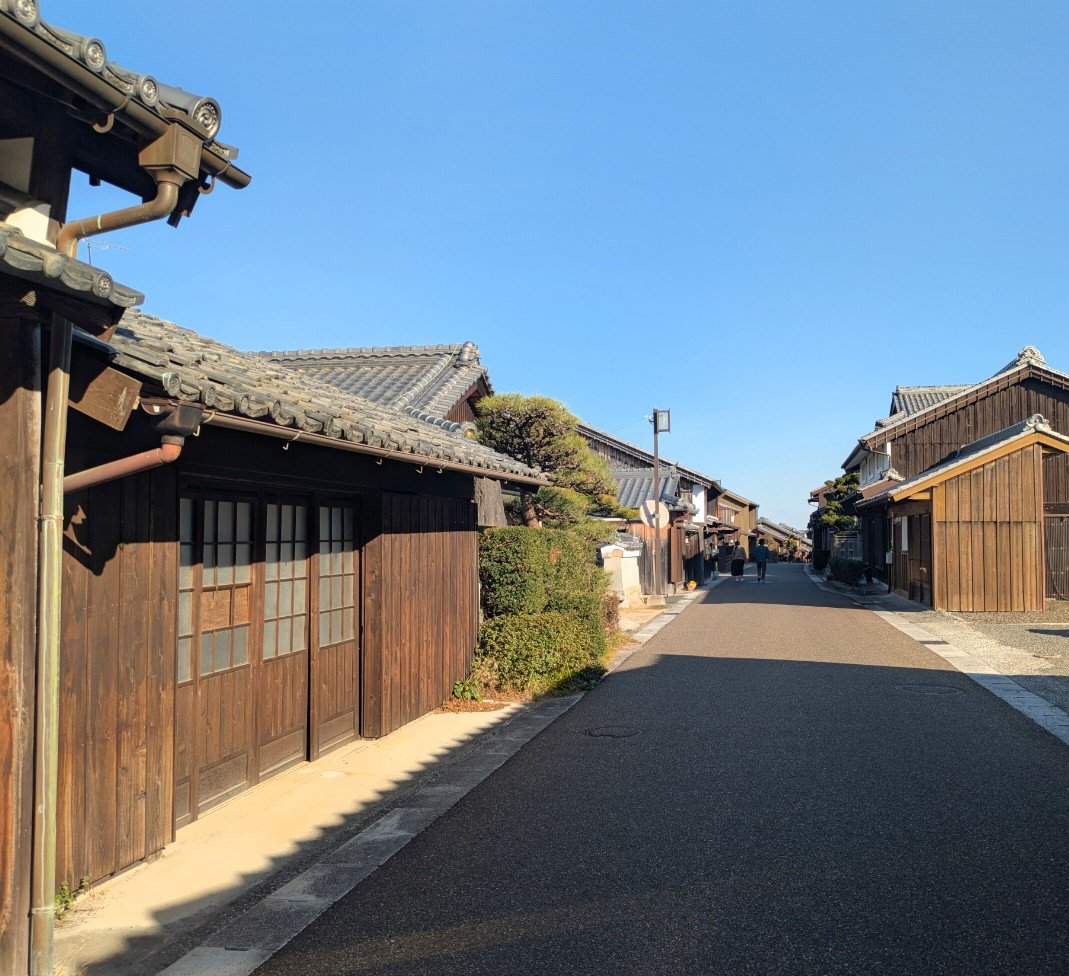 晴れた青空の下、瓦屋根の木造町家が両側に並ぶ関宿の一本道