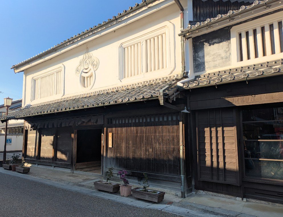 関宿の通りに面した白壁と瓦屋根の古い町家、虫籠窓と格子戸が並ぶ晴れた日の外観