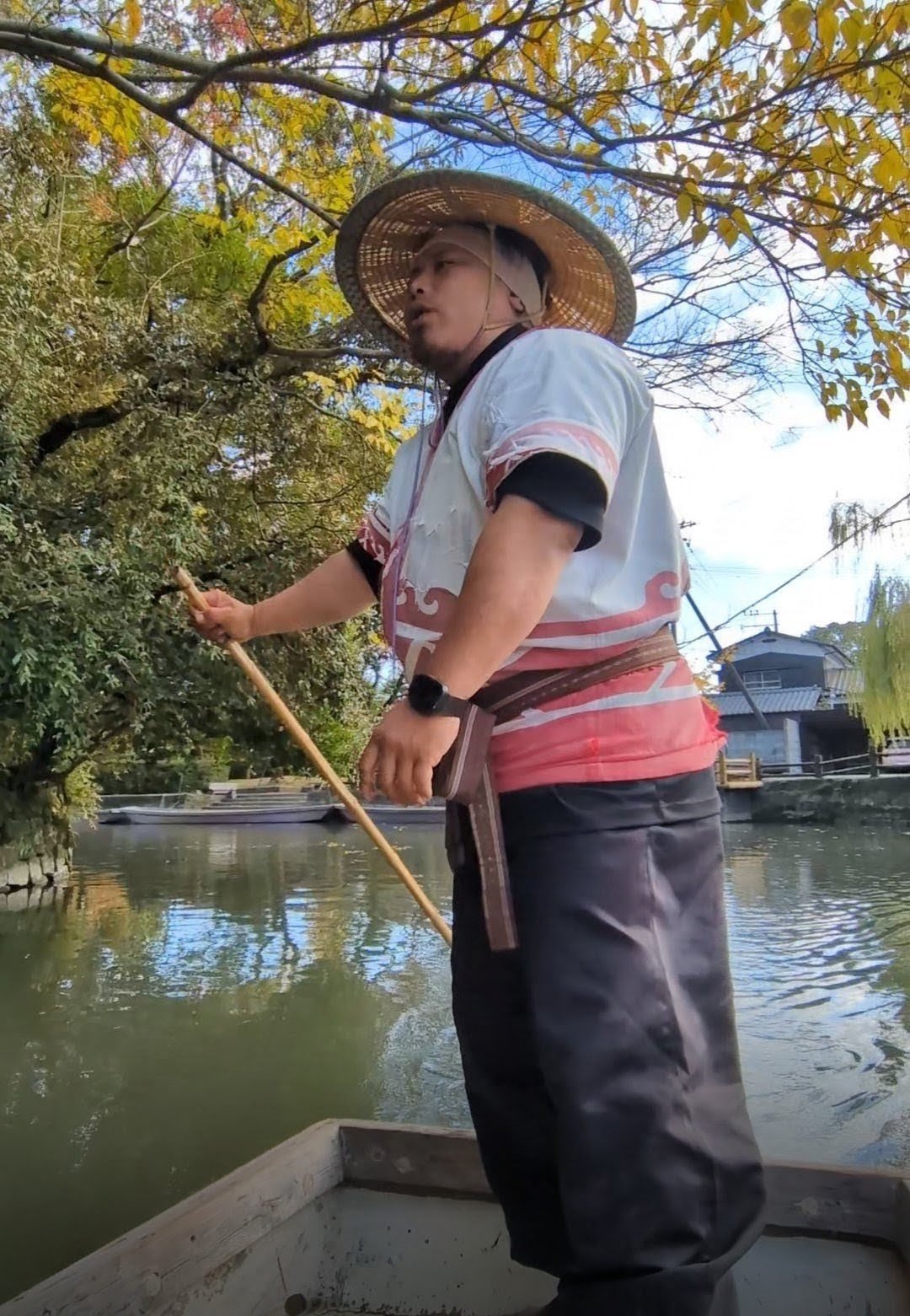 柳川の秋のお堀で竿を操りながら話す、笠をかぶった船頭
