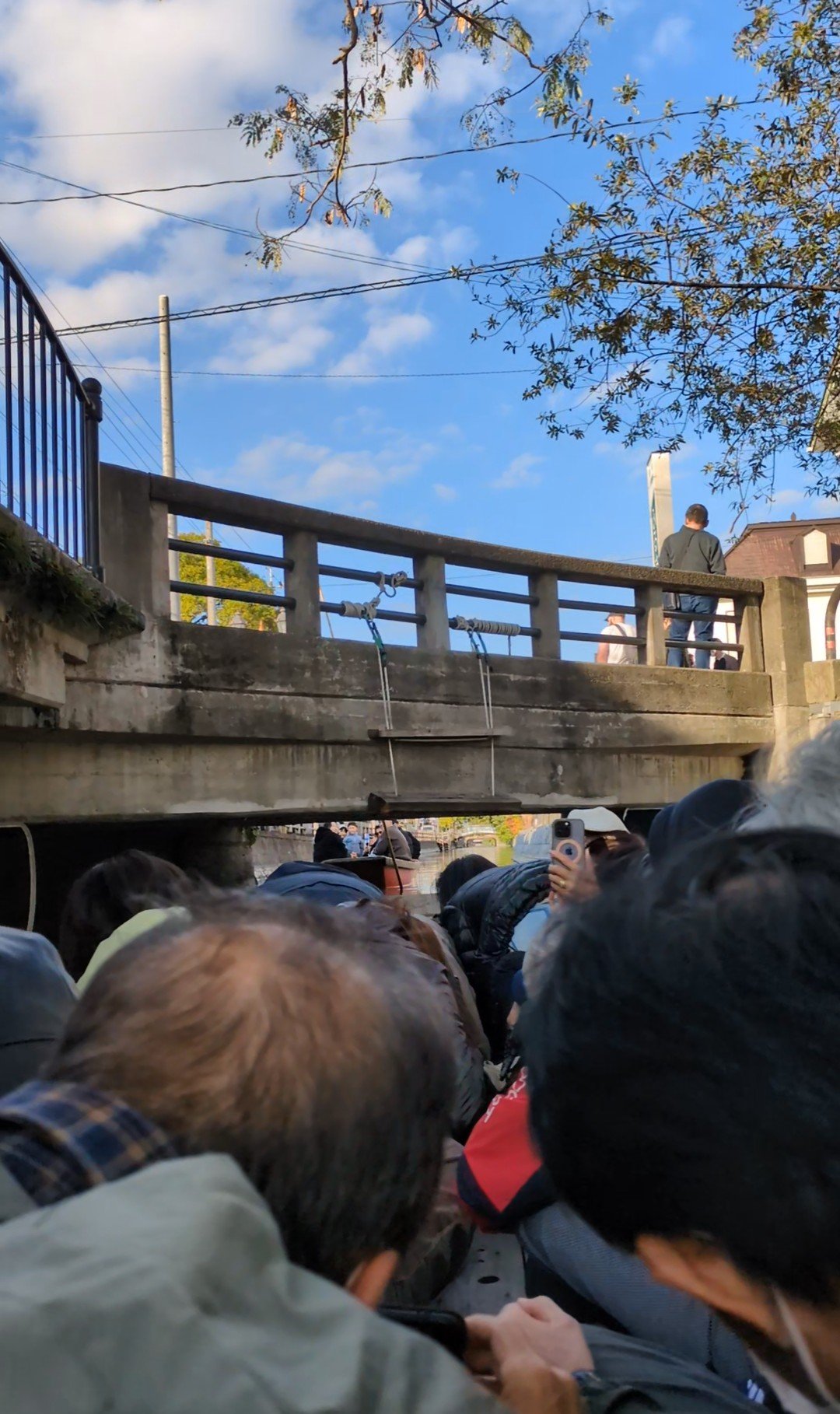 柳川の川下りで低い橋の下をくぐる船と、頭を伏せる乗客たち